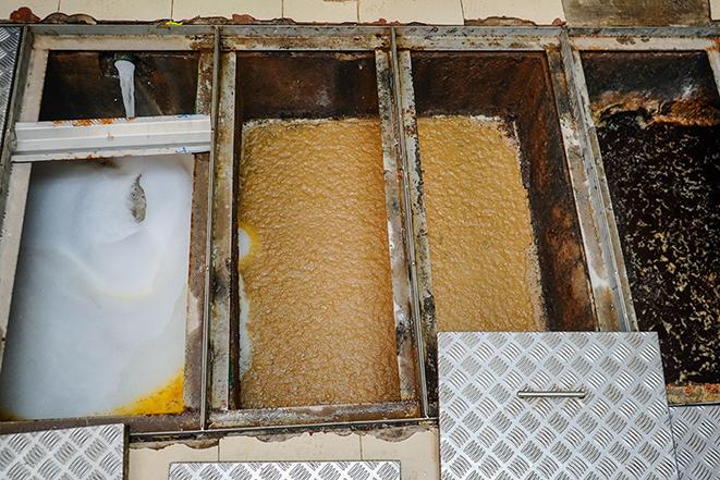 a greasy and grimy grease trap being thoroughly cleaned